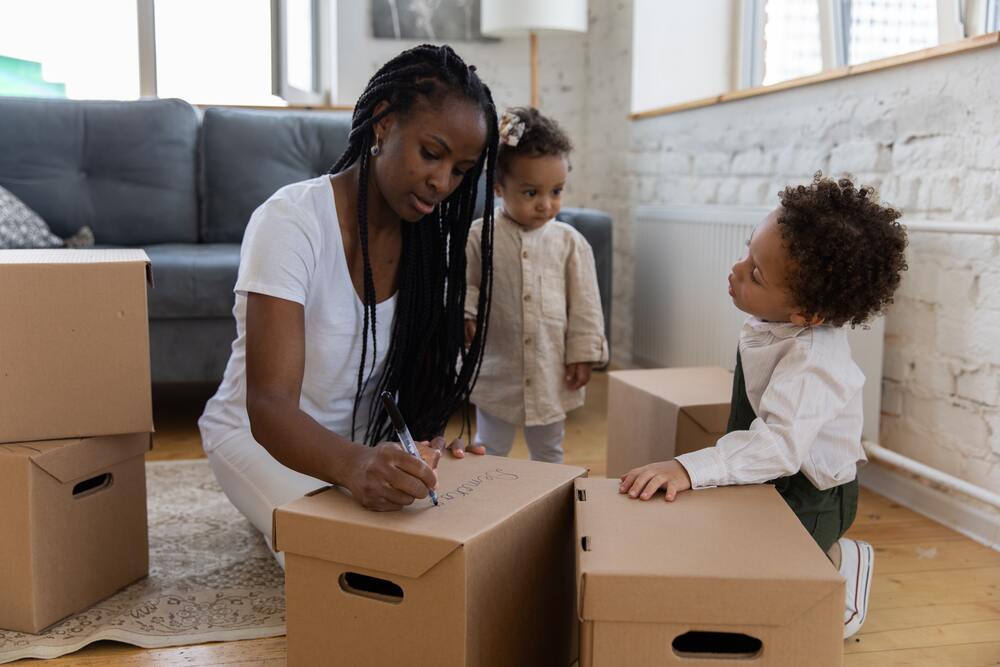 a woman labeling boxes with her kids before moving cross-country