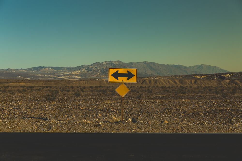 an image of a sign with two arrows facing either direction in a mountainous desert that represents how to change your life