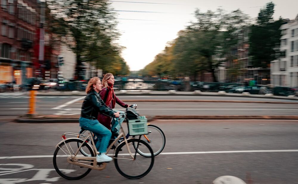 a photo of two girls biking in the city that represents a tip for how to budget money