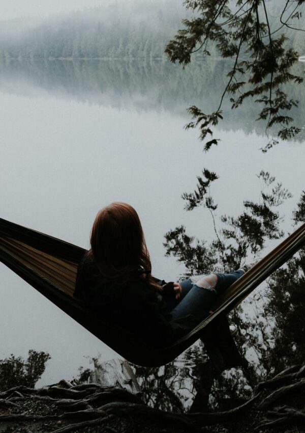 A woman sitting in a hammock overlooking the water that symbolizes minimalism