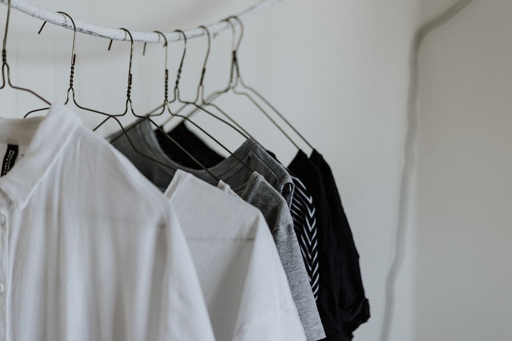 An image of shirts hanging on a clothing rack that represent a minimalist wardrobe