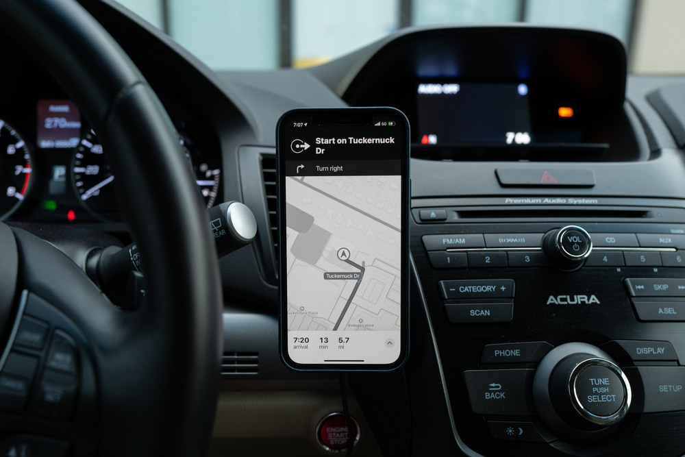 a phone in grayscale mode perched on a car dashboard with a GPS displayed on it 