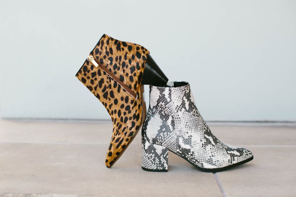 one leopard high heeled boot and one snake print boot that are stacked against one another that represent what not to own for a minimalist wardrobe