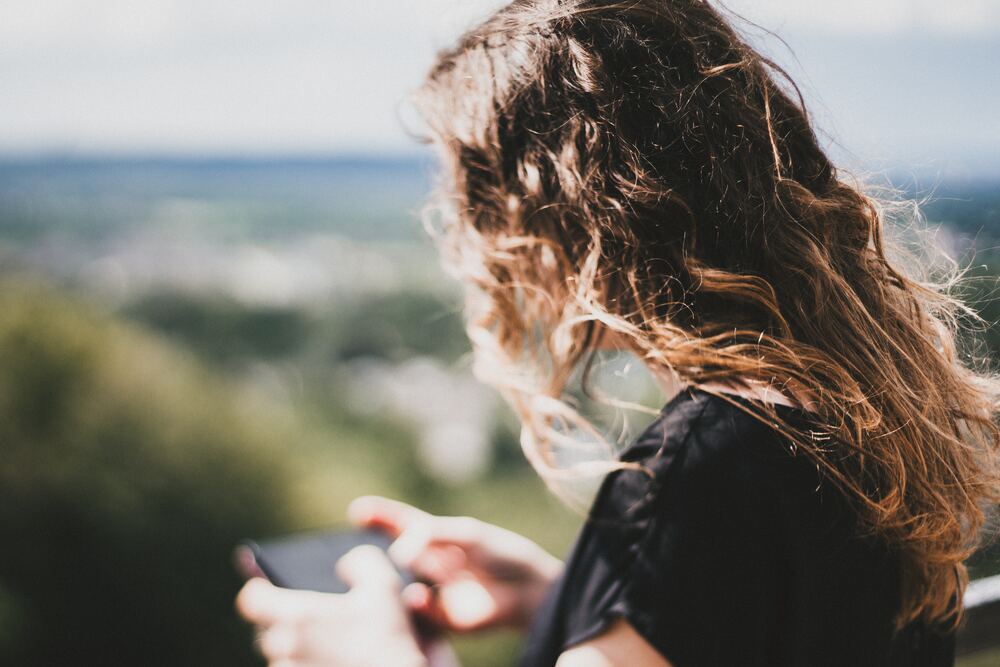 A girl scrolling on her cell phone outside that represents digital well-being