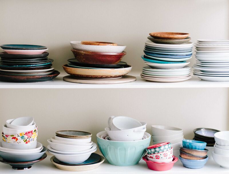 a cabinet full of dishes including mixing bowls, plates and bowls