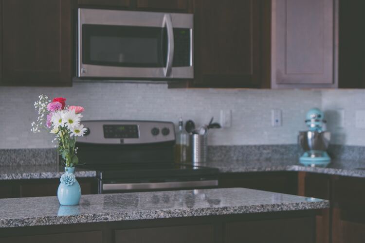 A minimalist kitchen with granite countertops and just a simple blue flower vase and standup mixer on the counters
