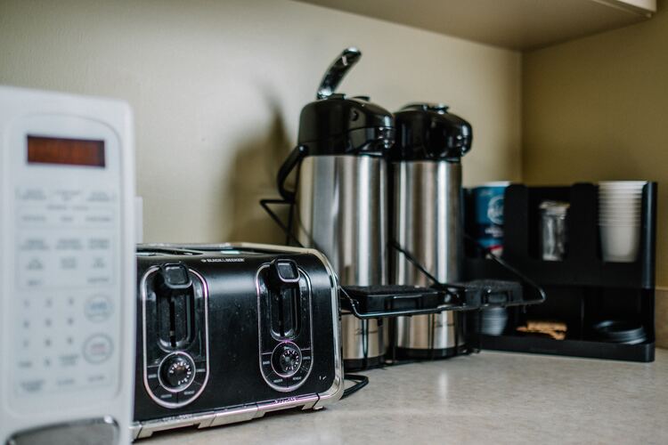Appliances sitting on a kitchen counter including a coffee station, toaster and microwave