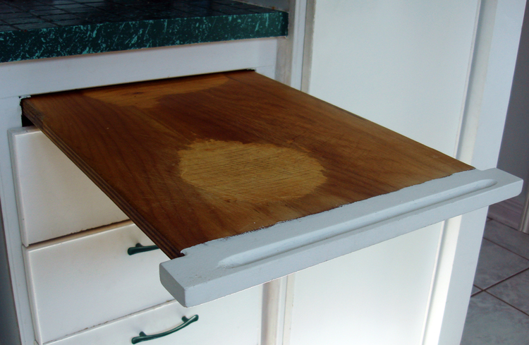 A pull out cutting board in a minimalist kitchen