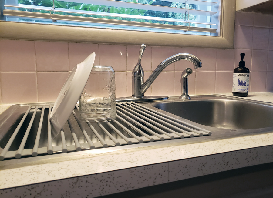 An over the sink dish drying rack in a minimalist kitchen
