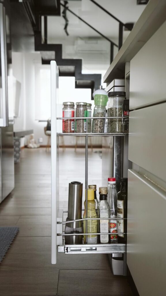 A slide-out pantry with spices and oils in a minimalist kitchen