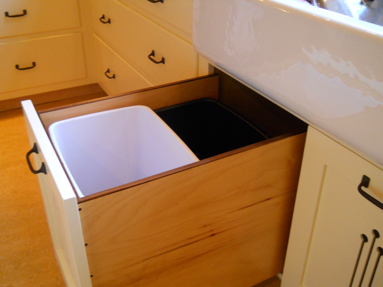 A pull out cabinet that has a recycling bin and trash bin in it in a minimalist kitchen