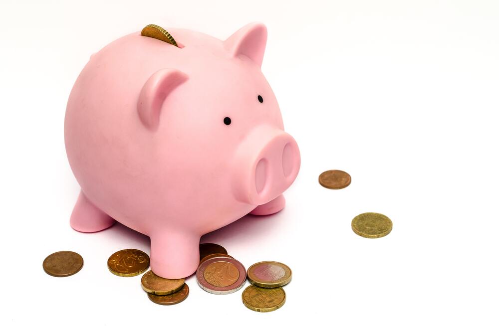 A pink piggy bank with coins all around it that represents saving money by budgeting using budget categories and subcategories. 