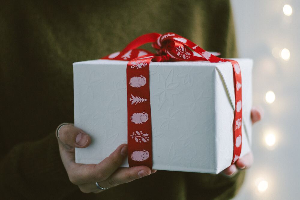 An image of a person holing a wrapped present with a red ribbon that represents stress-free holiday gift giving