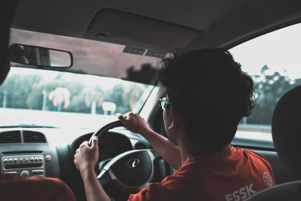 A close up image of a teenage boy driving