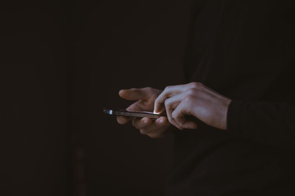 An image of hands scrolling on a phone against a black background that represents the 30-Day No Scroll Challenge