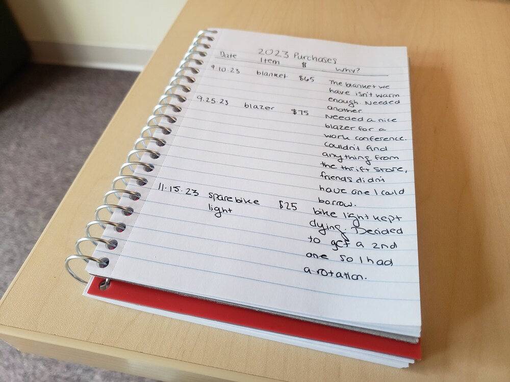 A notebook with a purchase list on it. Starting a purchase list is the fourth step in having a no-buy year. 