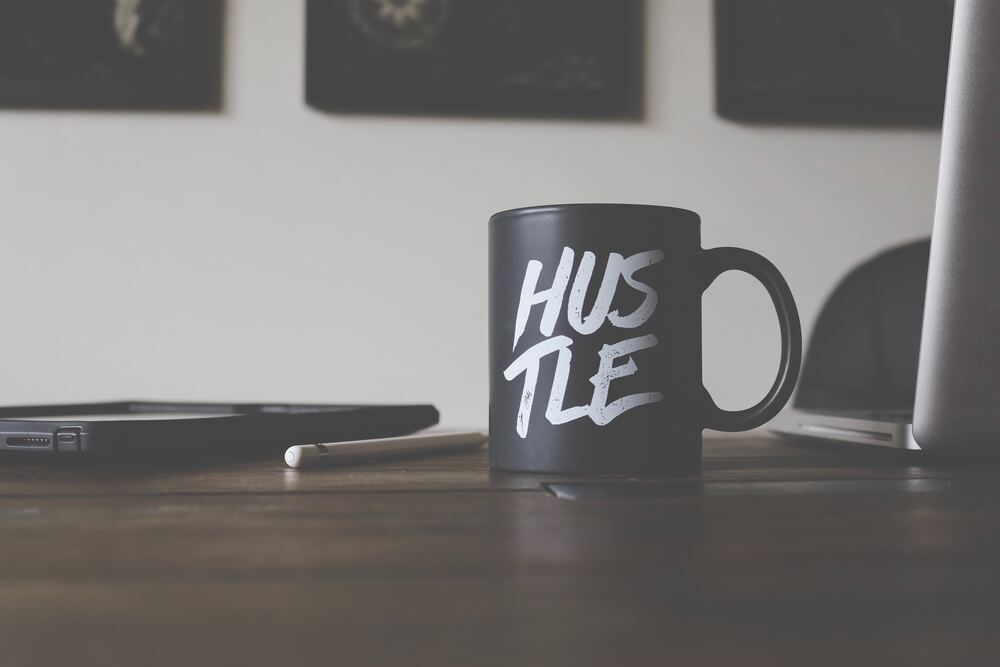 A cup that says 'hustle' on a desk