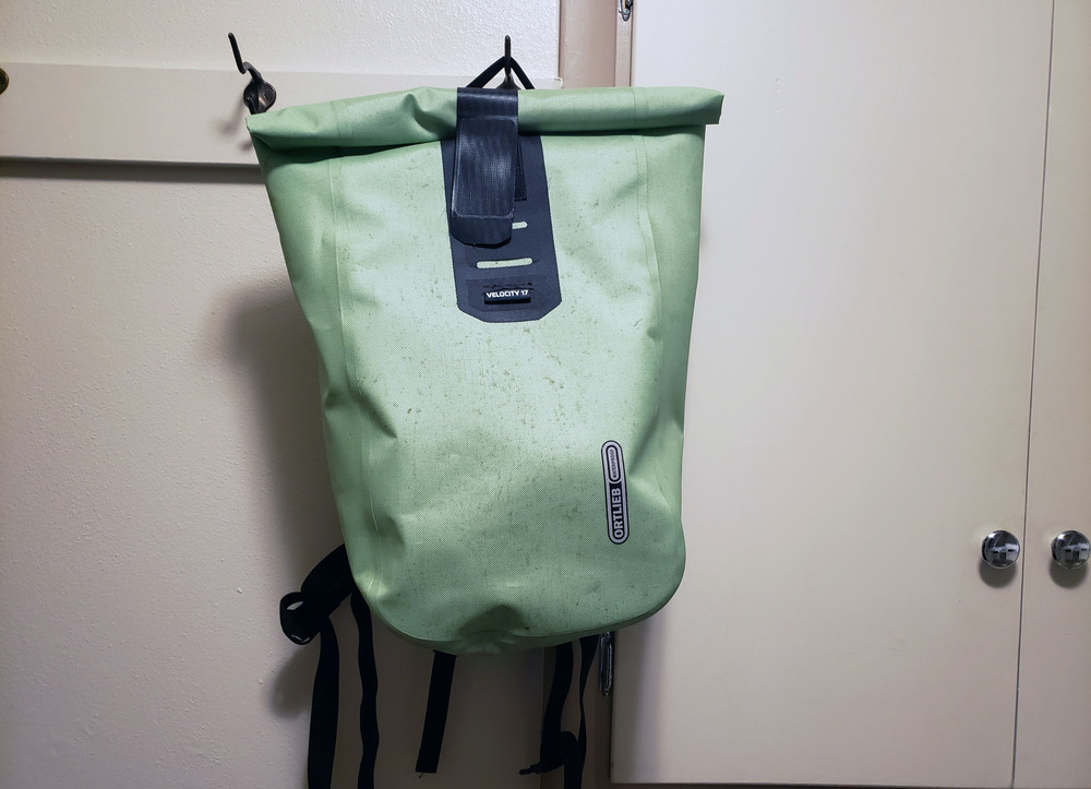 An image of a light green backpack hanging on a rack