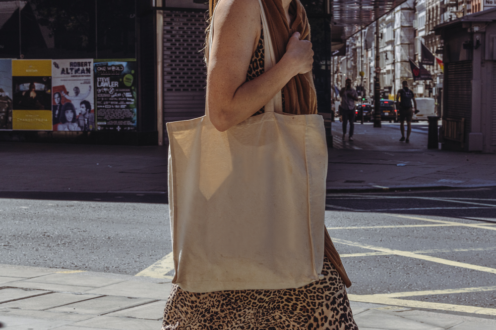 A woman holding a tote bag while walking around the city
