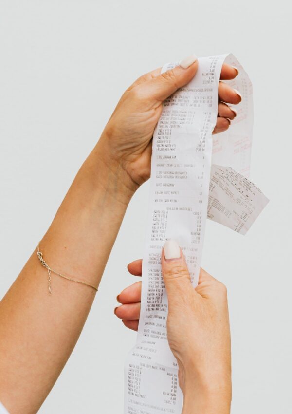 An image of a woman's hands holding a receipt up against a white background which signifies having a No-Buy Year