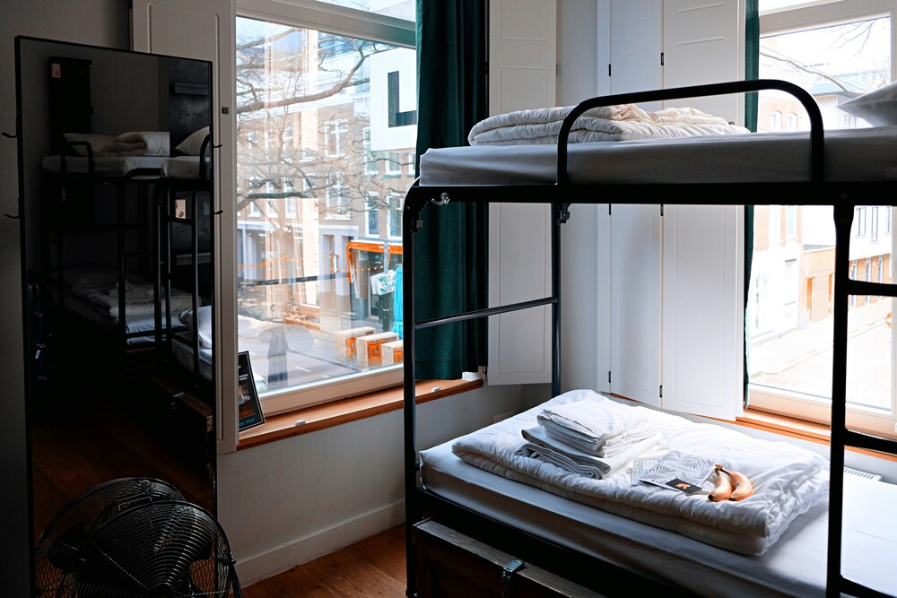 An image of a hostel. There is a bunk bed, mirror and window in the image.
