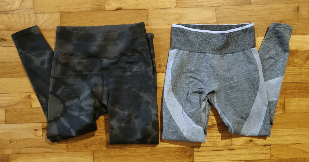 Two pairs of leggings folded beside one another against a wooden background