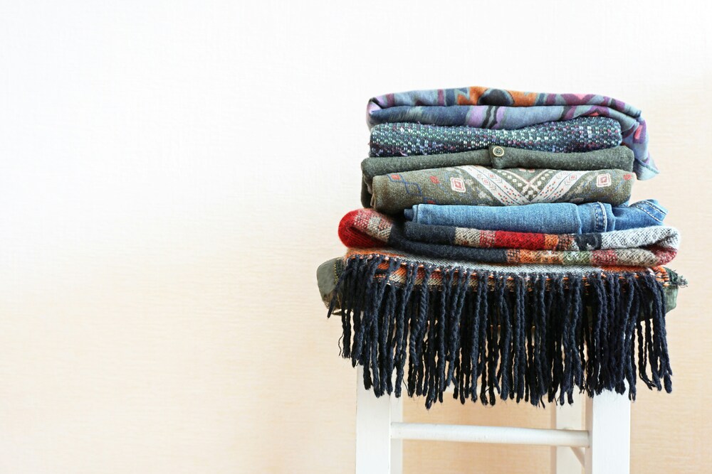 A stack of colorful sweaters and scarves that represent finding your authentic style as a minimalist