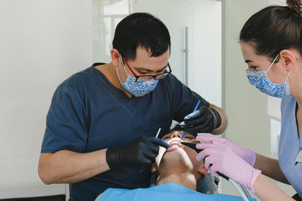 A dental assistant and dentist working with a patient